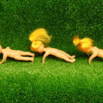 Plakat ze spektaklu Czekając trawnika. Na zielonym tle plakatu imitujące trawnik leżą na brzuchu trzy gołe lalki. Wszystkie mają żółte włosy spięte w kucyk.