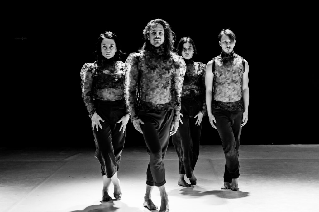 Czarnobiałe zdjęcie na którym znajduje się czterech tancerzy- dwie kobiety i dwóch męzczyz. Wszyscy ubrani są w spodnie oraz zwiewne bluzki.