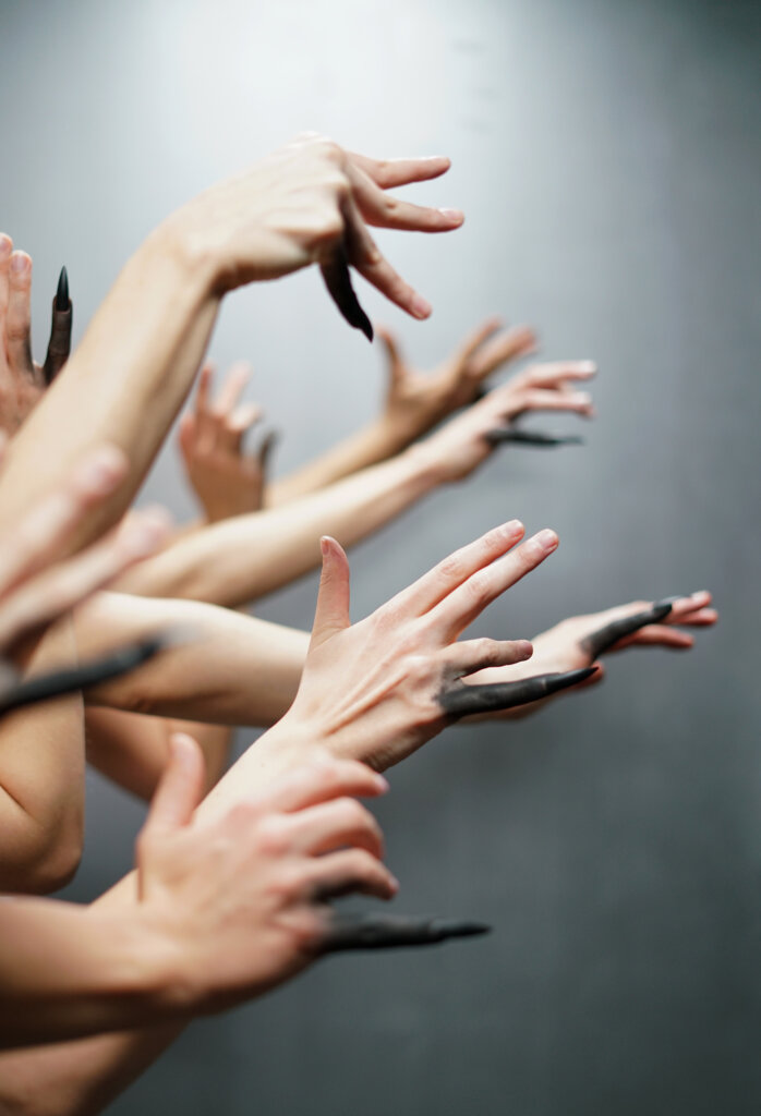 Pionowe zdjęcie, na którym znajdują się ręce tancerzy, gdzie palec mały jest pomalowany na czarno
