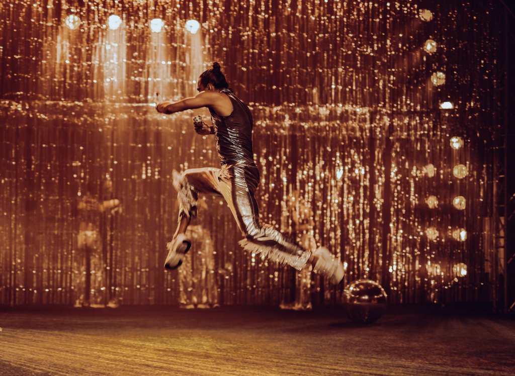 Zdjęcie ze spektaklu Fast Foot Fools. Na zdjęciu znajdije się tancerz ubrany na srebrno, który skacze.